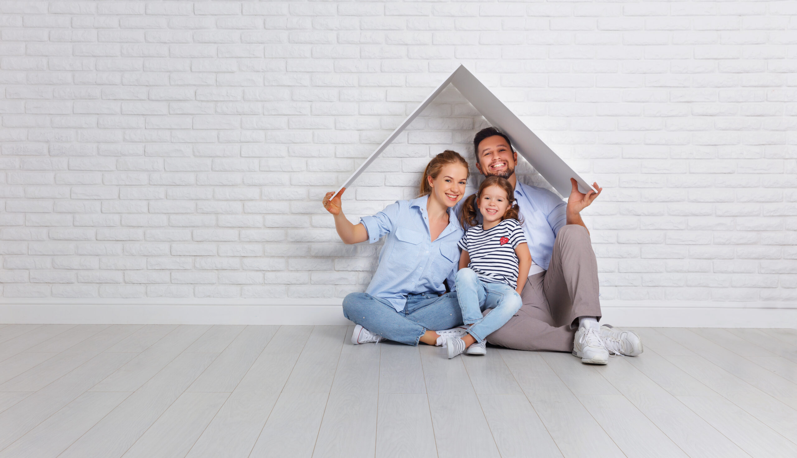 concept housing young family. Mother father and child in new house with roof at empty brick wall